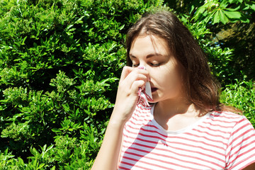 Woman with with allergy symptom blowing nose