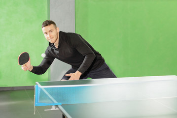 man playing ping pong. athlete beats a racket on the ball near the tennis table.