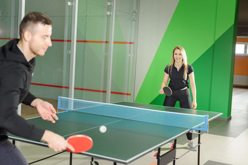 man and woman play ping pong. young guy holding a racket.