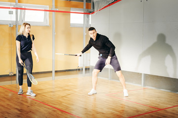 athletic man and woman playing squash.