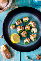 Bourguignonne snail with lemon. Blue wooden background.