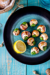 Bourguignonne snail with lemon. Blue wooden background.
