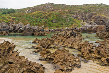 Formaciones rocosas en el agua.  Playa de Barro, ante el cerro El Pino, en Asturias