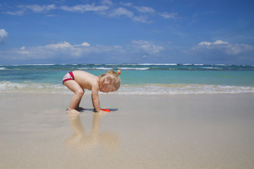Cute little girl enjoying a summer day on a sandy beach 