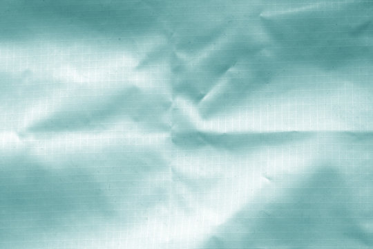 Crumpled transparent plastic surface in cyan color.