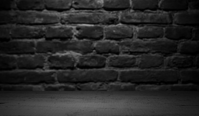 Old wood table with blurred concrete block wall in dark room background.