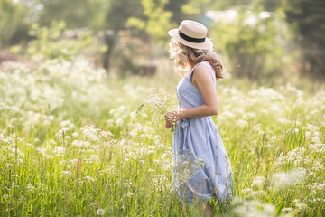Female portrait outdoors. the woman in the straw hat looks back into the distance. Flower field...
