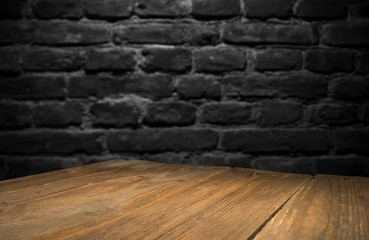 Old wood table with blurred concrete block wall in dark room background.