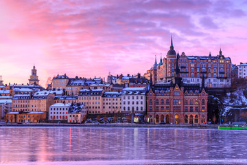Sodermalm island in Stockholm, Sweden. Beautiful orange, violet and pink sky at sunrise is reflected in frozen water of lake Malaren.