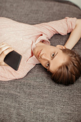 Caucasian young man using mobile phone while lying indoor. Corresponded, chatting or browsing. Concept browsing, rest, messenger. free wifi connection at home. Contemporary technology