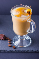 Copper coffee pot (Cezve) and coffee beans. Coffee with milk on dark background. Latte and black chocolate on slate board. Milk drink in glass beaker and dried rose