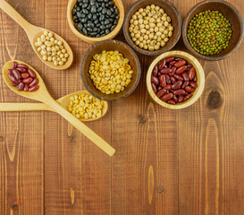 Flat lay,top view assorted beans including red bean,soybeans,black beans,mung beans on brown,beige wooden background with copy space 