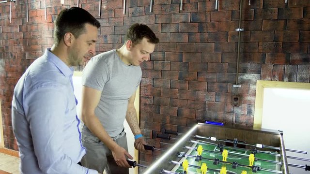 Sport, game concept. Foosball. Three men playing a table football or kicker with miniature players. 4K