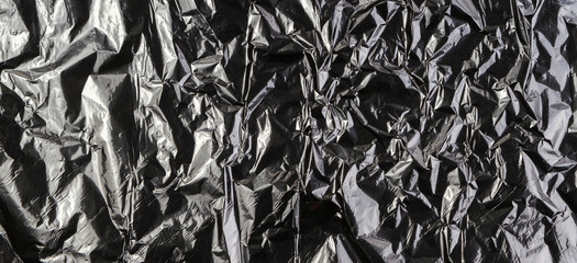 Black dark silver crumpled plastic material texture background