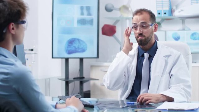 Physician wearing augmented reality glasses showing something to a patient. Future of medicine