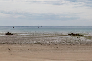 Looking out to sea over a sandy beach at low tide, on the Channel Island of Jersey