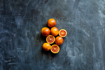 flat lay of red sliced exotic oranges, dark food on black surfaces