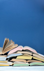 Open book, hardback colorful books on wooden table, blue background. Back to school. Copy space for text. Education business concept.