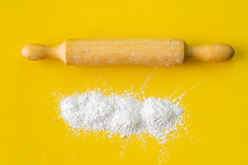 wooden rolling pin and white wheat flour on the table, equipment and ingredients for cookings
