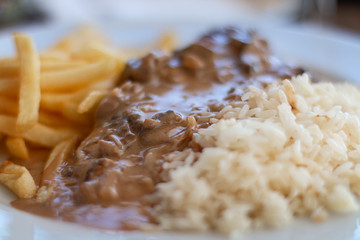 Single course with pork filet with mushrooms sauce, chips and rice.