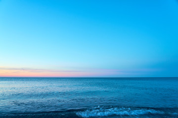 Fototapeta na wymiar Waving sea water on a sunset against a blue sky. Copy space. 