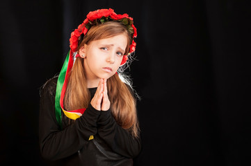 A sad girl prays on a dark background. The girl prays for no war on the whole earth