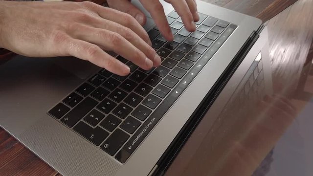 FIngers typing on laptop keyboard. Smooth and stabilized dolly shot of keyboard. 