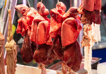 Meat concept. Fresh liver of lamb, sheep, pork, beef hanged on hooks at butcher shop.