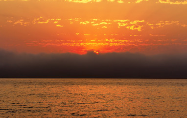 beautiful red sunset, dark clouds and ocean on the horizon