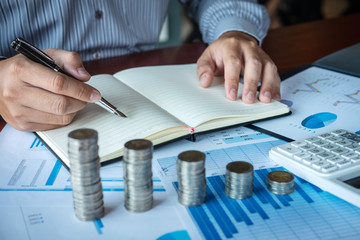 Businessman accountant counting money and making notes at report doing finances and calculate about...