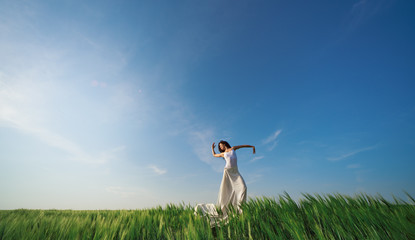 Yoga and fit. Flying dancer in the air. Happy woman ballerina in white fabric skirt posing on Green field. Summer or concept