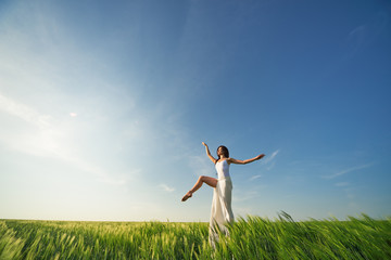 Yoga and fit. Flying dancer in the air. Happy woman ballerina in white fabric skirt posing on Green field. Summer or concept