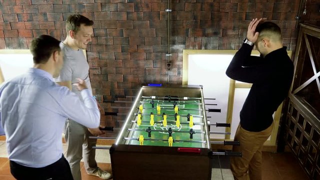 Sport, game concept. Foosball. Three men playing a table football or kicker with miniature players. 4K