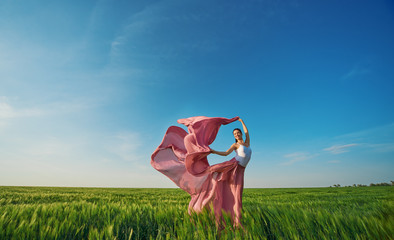 Classic dance on nature background. Professional female modern dancer in pink fabric dress dancing...
