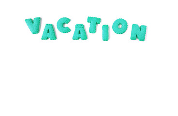 The word VACATION spelled with vibrant aqua blue color alphabet shaped cookies on white background