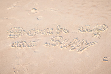 The Words "Soak Up the Sun" Written in the Sand