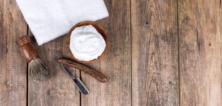 Wooden shaving razor with shaving brush and shaving foam on a rustic wooden table - vintage shaving accessories - top view