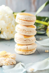macarons and white peony flowers on wooden surface   