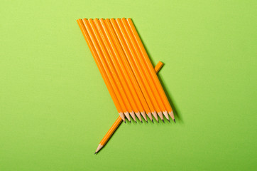 Yellow pencil isolated on green background. Minimalist template with copy space.