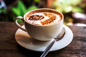 a cup of hot coffee in warm sunlight ambient on brown wooden table.