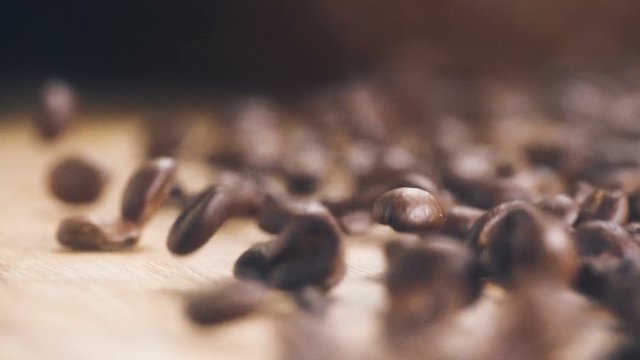 Roasting brown Coffee Beans with steam. tracking shot, close up - super slow motion. beans falling on wooden table