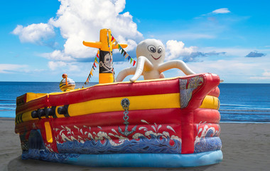 Nadmuchiwana łódź, statek kolorowa zjeżdżalnia dla dzieci  nad morzem i błękitnym niebem