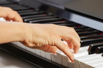 Close up view of kid hands playing on piano keyboard