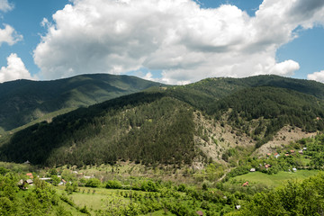 Fototapeta na wymiar Landscape of Zlatibor Mountain. Green meadows and hills under blue sky with clouds in springtime