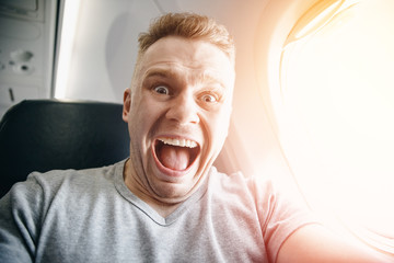 Passenger man in plane clutches his head, afraid of heights and flight. Scream and cry expression