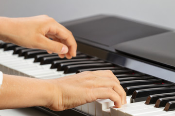 Fototapeta na wymiar Close up view of kid hands playing on piano keyboard