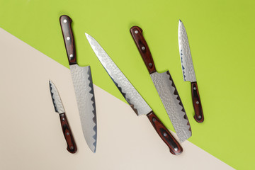 Several different used stainless steel kitchen knives with brown wooden handles