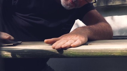 Close up of adult man caring about his outdoor furniture - handmade grinding with abrasive paper. Close up shot.