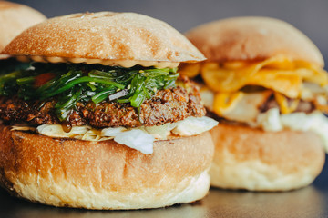Burger flyer. Cheese burger with grilled meat, cheese, salad and onion rings. Close-up of delicious fresh home made burger with salad and cheese on bark blue background