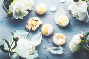 Draufsicht von macarons und von weißen Pfingstrosenblumen auf Holzoberfläche